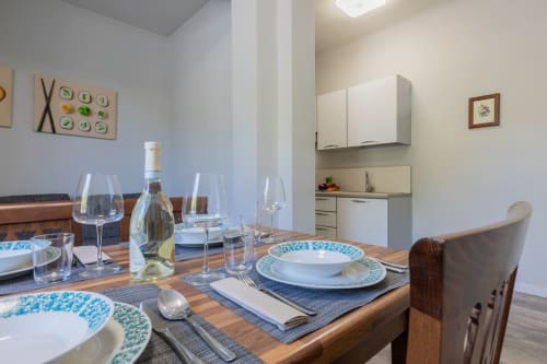 Elegante sala da pranzo dell'hotel Prince Garda con tavolo in legno, apparecchiatura, bottiglia di vino e cucina moderna a Serniga