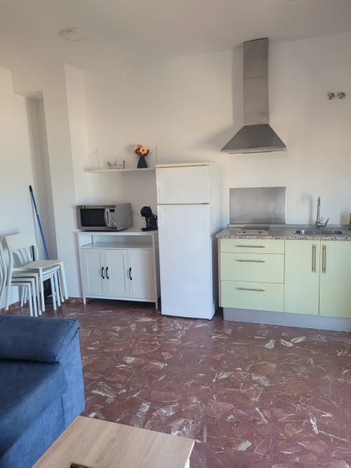Cocina moderna con armarios verdes, microondas y campana extractora en apartamento frente al mar en Matalascañas