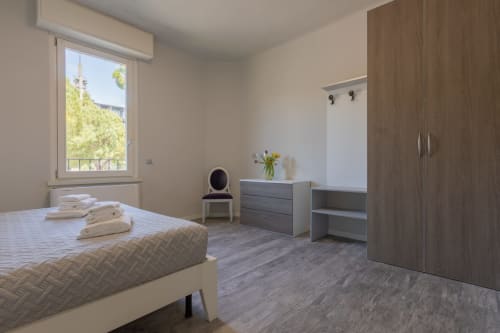 Camera moderna dell'hotel Prince Garda a Serniga con letto, armadio in legno, cassettiera e finestra con vista paesaggistica