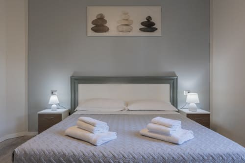 Camera da letto con atmosfera spa presso l'Hotel Prince Garda, con opera d'arte in pietra stratificata, biancheria di lusso e asciugamani arrotolati sul letto