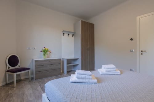 Camera moderna dell'hotel Prince Garda a Serniga con letti gemelli, armadio, cassettone e poltrona
