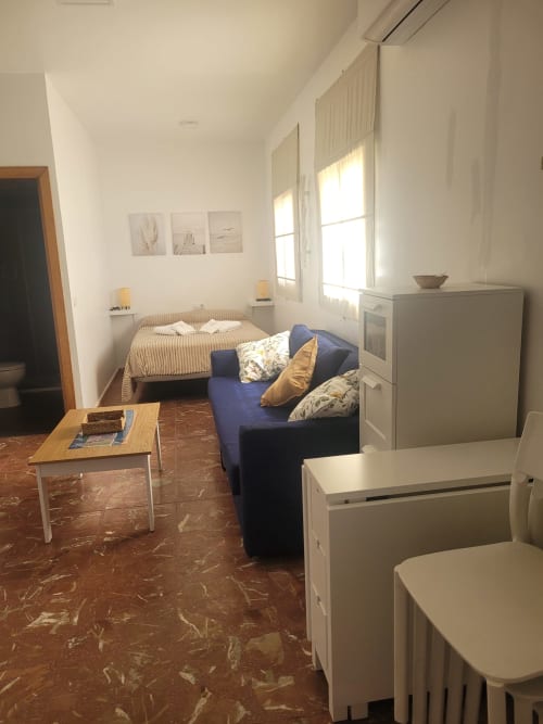 Sala de estar de estudio con sofá, cama, cocina americana y vistas al mar en Apartamentos A la Orilla del Mar, Matalascañas
