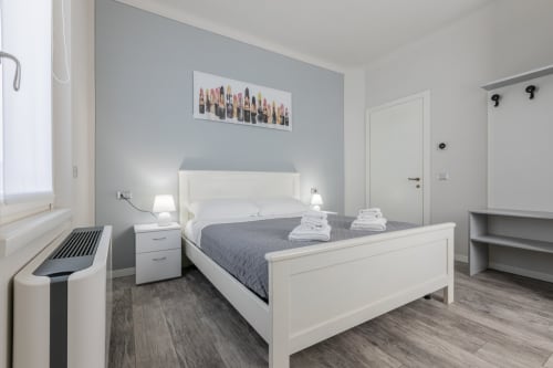 Camera dell'hotel Prince Garda a Serniga con letto bianco, parete grigia d'accento e arredi moderni