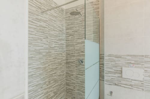 Bagno moderno con doccia a piastrelle righe presso l'hotel Prince Garda, Serniga