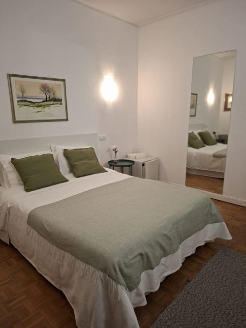 Porta 80 House deluxe double bedroom in Braga with bed, green pillows, mirror, and woodland artwork