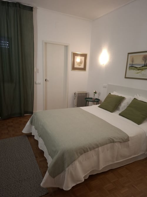 Porta 80 House Braga Deluxe double room with bed, green pillows, framed artwork, and modern lighting