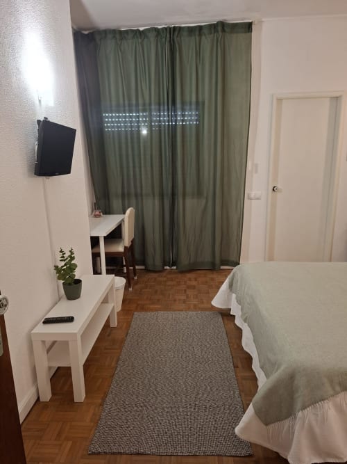 Porta 80 House Deluxe bedroom in Braga with bed, desk, TV, green curtains and wooden floors
