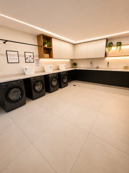 Sala de lavanderia moderna com máquinas de lavar frontais pretas e marcenaria creme em apartamento de Brasília