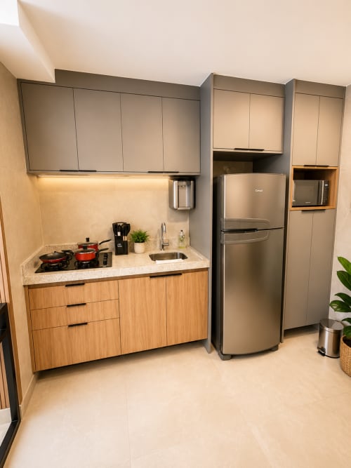 Cozinha moderna compacta em apartamento de Brasília com geladeira inox, fogão a gás e armários em madeira