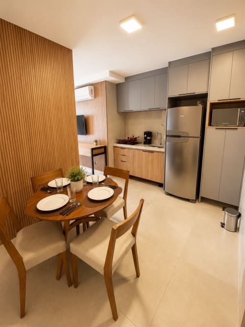 Cozinha e sala de jantar modernas em apartamento de Brasília com mesa de madeira, eletrodomésticos em aço inoxidável e móveis cinzento