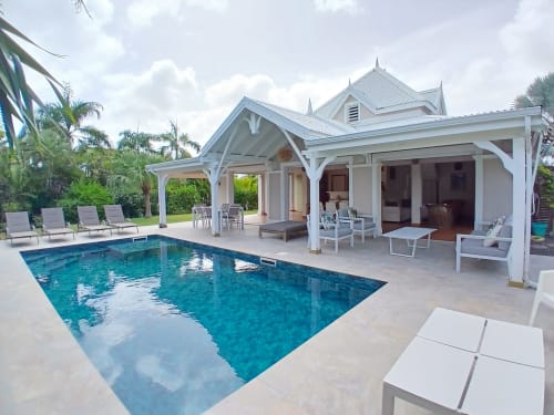 Luxury villa at ILMO Conciergerie in Le Gosier with pristine pool, covered patio, lounge chairs, and tropical palm trees