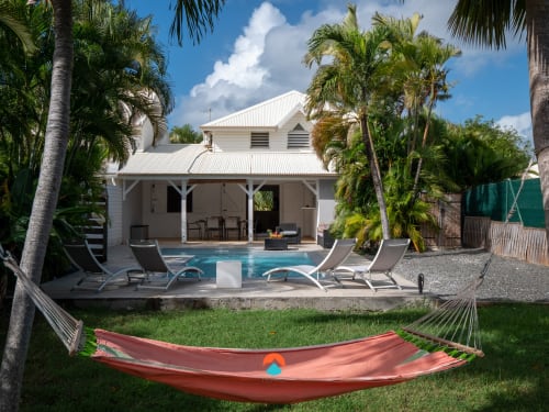 ILMO Conciergerie property in Le Gosier with poolside lounge area, hammock, and white colonial-style house