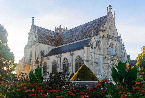 Chapelle gothique aux tuiles de toit bleu orné et fleurs colorées à la propriété Systeo en France