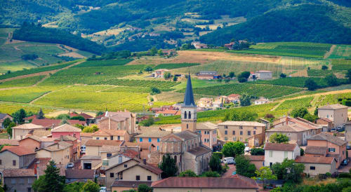 Vue aérienne d'un charmant village français avec toits en terre cuite, clocher et vignobles ondulants à la campagne