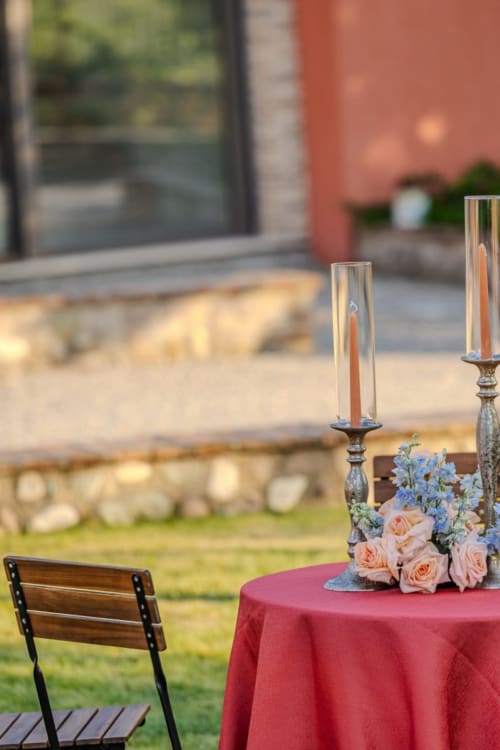 Elegante cena all'aperto presso Corte Baruzzo Relais con tavolo illuminato da candele, rose rosa e vista sul cortile a Volta Mantovana