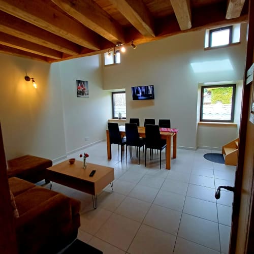 Vaste séjour ouvert avec poutres en bois, salle à manger, coin détente et vue sur le jardin aux Gîtes Du Couvent