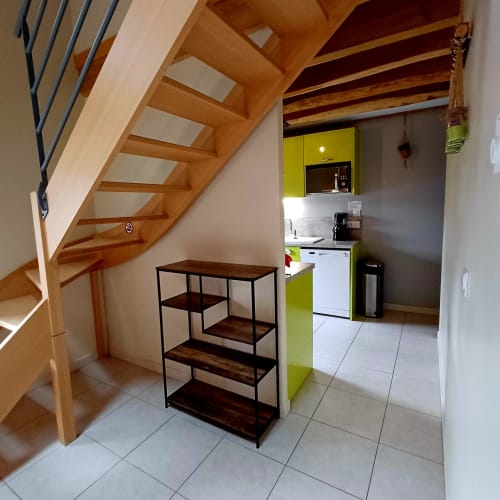 Cuisine cottage moderne et séjour avec escalier en colimaçon en bois, placards vert anis lumineux et étagères à Les
