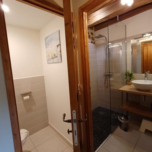 Salle de bain moderne aux Gîtes Du Couvent avec douche à l'italienne, poutres en bois, vasque design et sèche-serviettes électrique