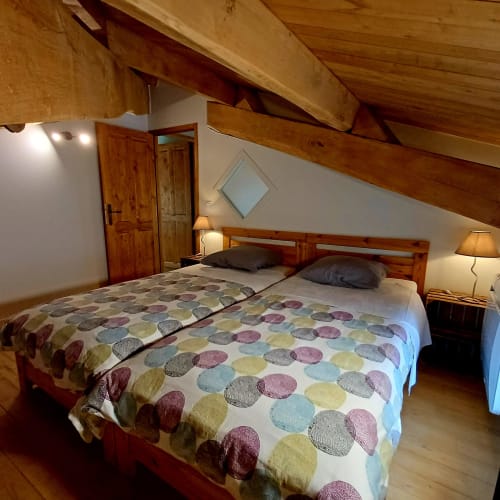 Chambre douillette à la mansarde du Gîte du Couvent avec poutres apparentes, lit queen-size et vue sur le jardin à Nozières