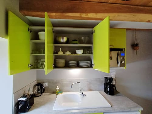 Cuisine moderne avec portes de placard vert citron brillant ouvertes, présentant des assiettes et bols blancs. Évier et plan de travail blanc.