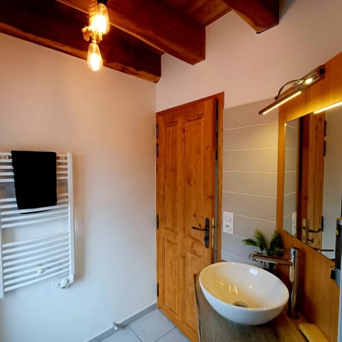 Salle de bain moderne aux Gîtes Du Couvent avec vasque blanche, miroirs en bois, porte-serviettes chauffant et bois rustique