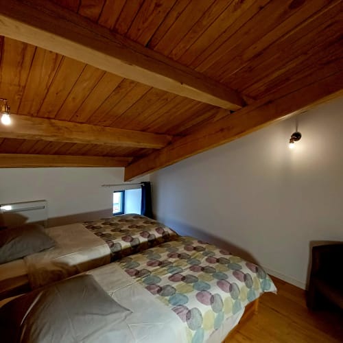 Chambre douillette aux Gîtes Du Couvent avec plafond à poutres en bois, lits jumeaux et murs blancs en Ardèche, France