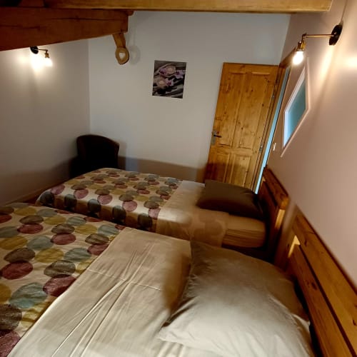 Chambre cosy avec lits jumeaux aux Gîtes Du Couvent, gîte ardéchois avec mobilier en bois et literie à motifs