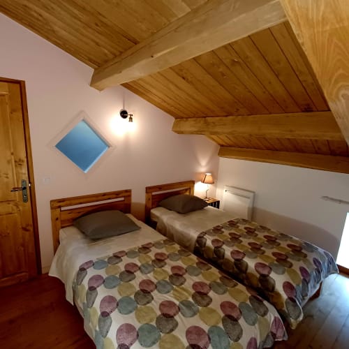 Chambre cosy avec deux lits simples, poutres en bois et vue montagne aux Gîtes Du Couvent en Ardèche, Nozières