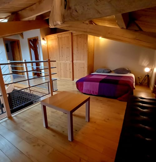 Chambre spacieuse avec poutres bois, lit violet et mezzanine aux Gîtes Du Couvent en Ardèche