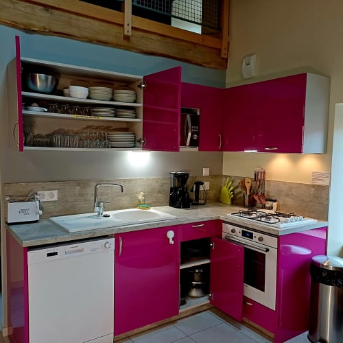 Cuisine moderne aux armoires magenta éclatant, électroménagers en acier inoxydable et étagères ouvertes aux Gîtes Du Couvent