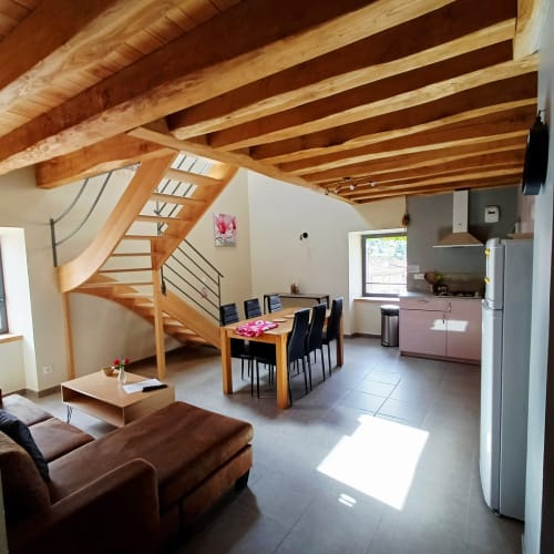 Intérieur de gîte moderne avec poutres en bois, escalier en spirale, salle à manger et cuisine aux Gîtes Du Couvent, Ardèche