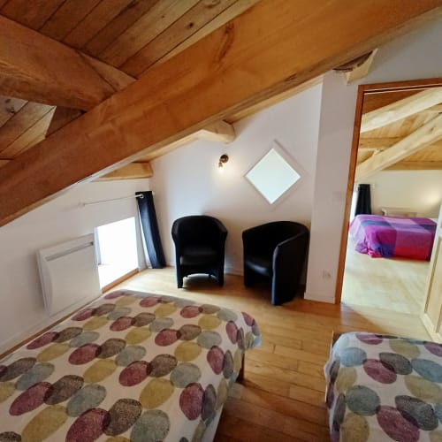 Chambre mansardée aux Gîtes Du Couvent, Ardèche : poutres apparentes, lits jumeaux avec parure motifs, ambiance noire