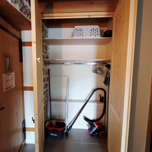 Armoire en bois ouverte avec étagères, cintres et paniers de rangement dans le gîte 3 des Gîtes Du Couvent, Ardèche