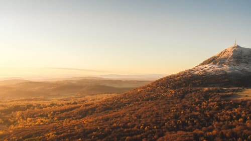 Coucher de soleil doré sur un paysage volcanique avec chapelle, Les 3 Volcans, Clermont-Ferrand