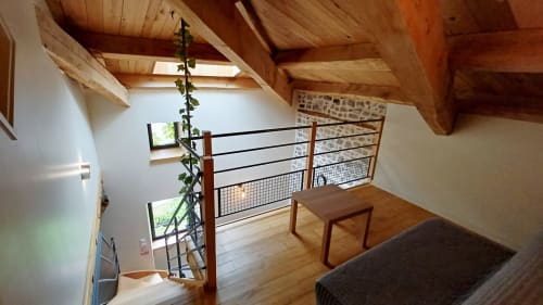 Chambre en mezzanine avec poutres bois, balustrade, vue sur terrasse et mur en pierre brute à la maison Ardèche