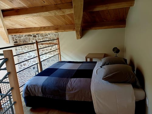 Chambre douillette aux Gîtes Du Couvent avec poutres en bois, linge de lit bleu et murs en pierre en Ardèche