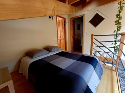 Chambre spacieuse aux Gîtes Du Covent avec lit queen-size, poutres en bois et mobilier moderne à Nozières, Ardèche