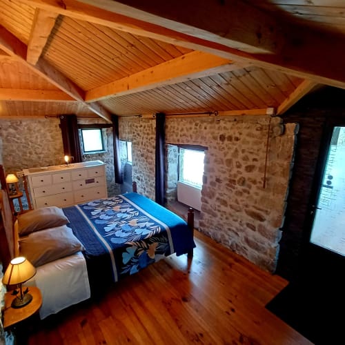 Chambre familiale spacieuse aux Gîtes Du Couvent avec murs en pierre apparente, poutres en bois et parquet en Ardèche