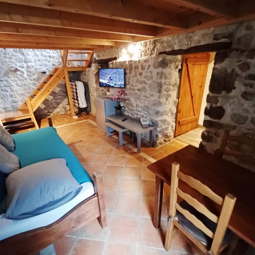 Chambre familiale en pierre et bois aux Gîtes Du Couvent avec TV, coin salon et charme rustique à Nozières, Ardèche