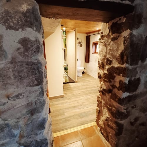 Entrée en pierre voûtée de la Chambre d'hôtes familiale aux Gîtes Du Couvent, Ardèche, avec sol en bois et design moderne