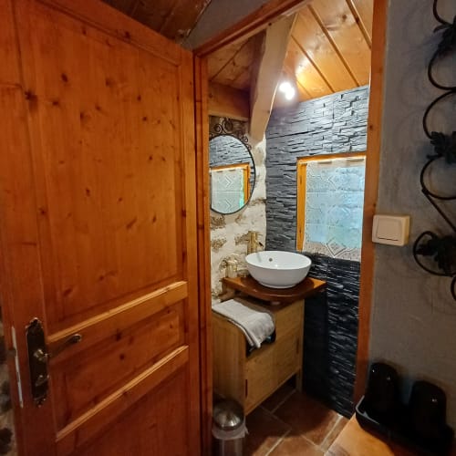 Salle de bains moderne aux Gîtes Du Couvent avec vasque blanche, mur d'accent en carrelage noir, meuble de salle de bain en bois et miroir décoratif