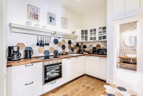 Cucina moderna bianca con piastrelle esagonali, banconi in legno e elettrodomestici in acciaio inossidabile nell'appartamento Rome to You