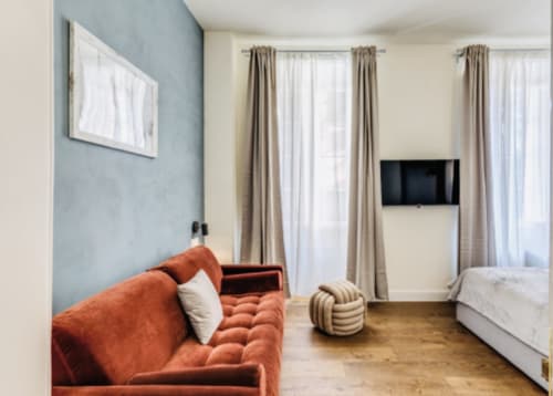 Zona living moderna con divano arancione, TV a muro e camera da letto presso Rome to You B&B a Monte Sacro
