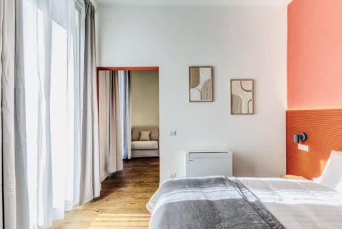Camera da letto moderna nell'appartamento Rome to You con pavimenti in legno, parete accent arancione, specchio e zona soggiorno aperta a Monte Sacro