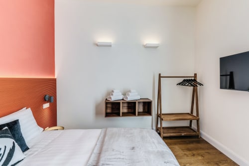 Camera moderna presso Rome to You B&B con letto bianco, appendiabiti in legno, scaffali a muro e parete accent color corallo a Monte