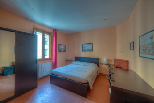 Bright bedroom at Sogni D'Oro Guest House in Florence with blue bed, peach walls, and arched ceiling