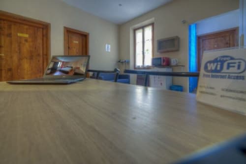 Zona comune della Guest House Sogni D'Oro a Firenze con porte in legno, laptop, accenti blu e cartello WiFi gratis