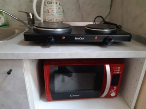 Fornello a due piastre neri e microonde rosso nella cucina della Guest House Sogni D'Oro, Firenze