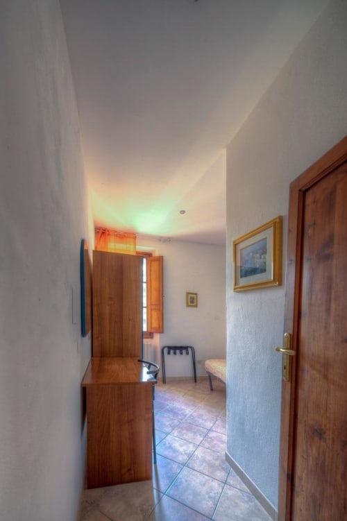 Corridoio luminoso della Sogni D'Oro Guest House a Firenze con porte in legno, opere d'arte incorniciate e luce naturale calda