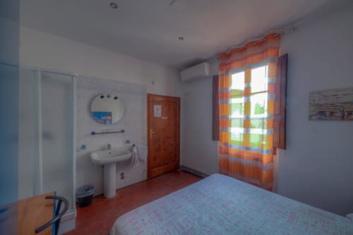 Camera da letto con bagno privato, letto e tende a righe arancioni presso la Guest House Sogni D'Oro a Firenze